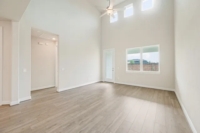 an empty room with wooden floor chandelier and windows