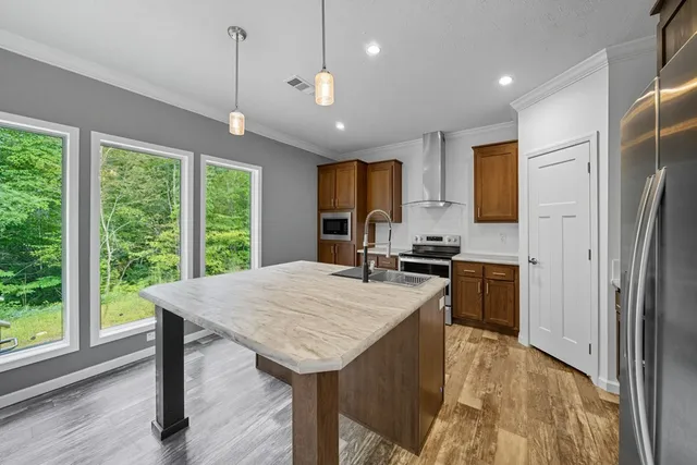 a kitchen with stainless steel appliances granite countertop a refrigerator a sink dishwasher a stove and a refrigerator with wooden floor