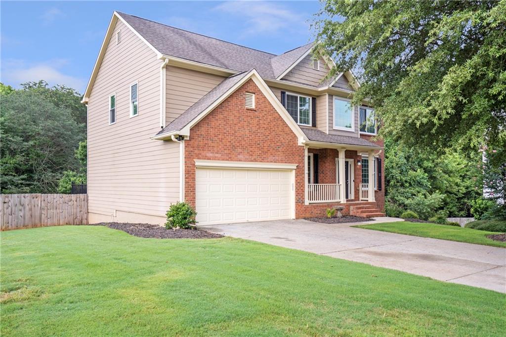 a view of a yard in front of a house with plants and large tree