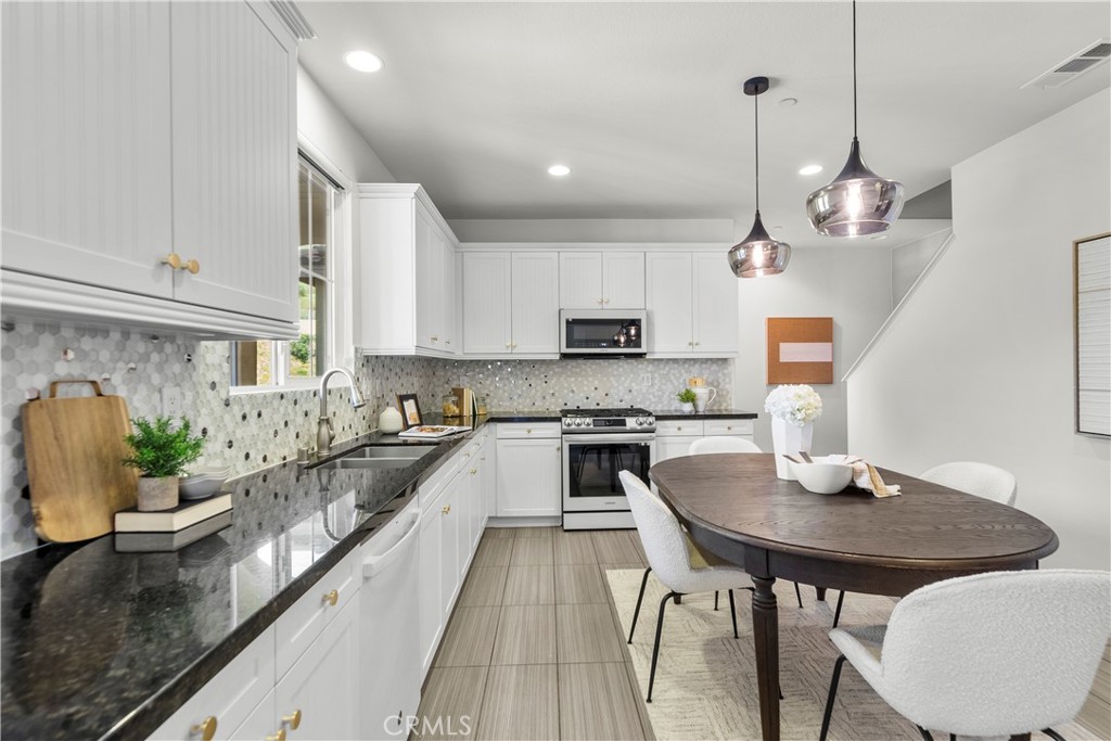 22157 Barrington Way Saugus, CA 91350 - Photo 21 of 46 a kitchen with stainless steel appliances granite countertop a stove top oven a sink a dining table and chairs with wooden floor