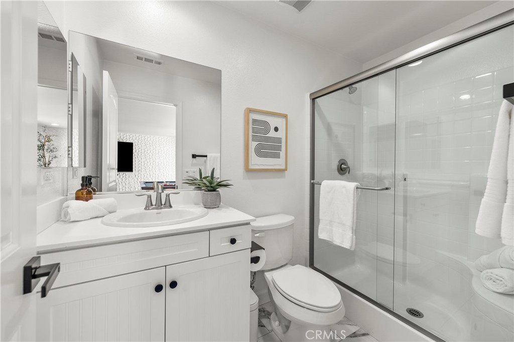 22157 Barrington Way Saugus, CA 91350 - Photo 9 of 46 a bathroom with a toilet a sink a mirror and a shower