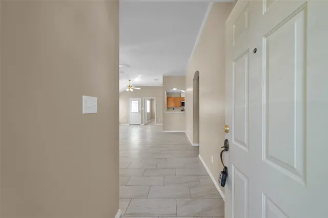 a view of an empty room with chandelier fan and windows