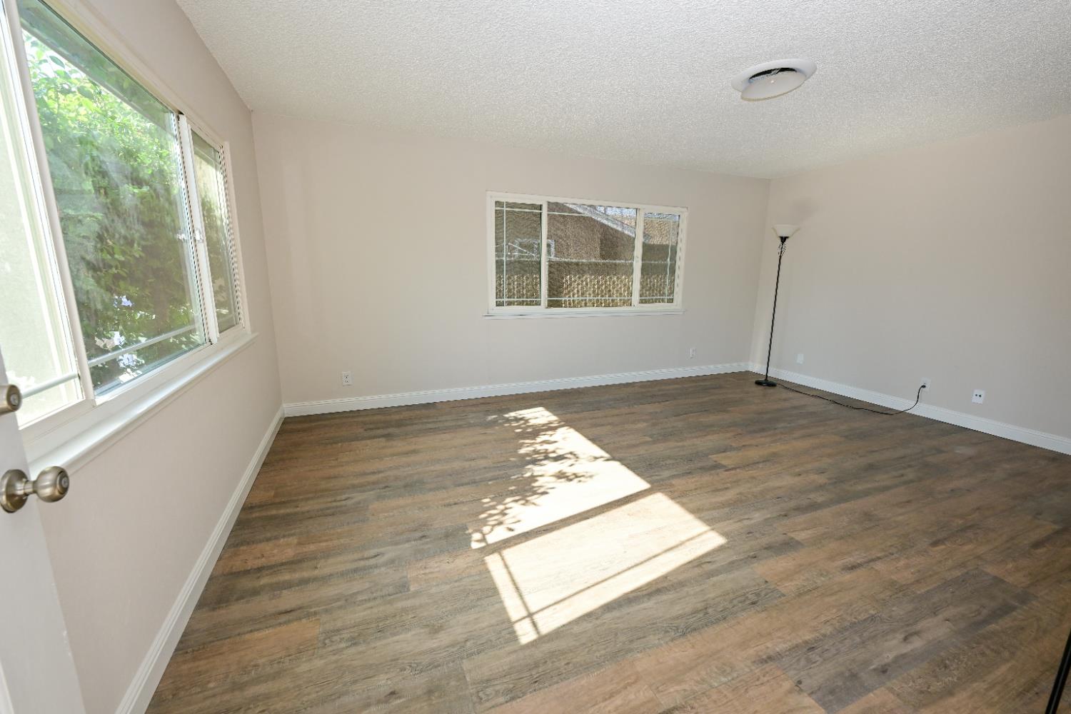 133 10th Street Clovis, CA 93612 - Photo 3 of 17 an empty room with wooden floor and windows