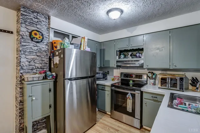 a kitchen with stainless steel appliances granite countertop a refrigerator a stove and a sink with wooden floor