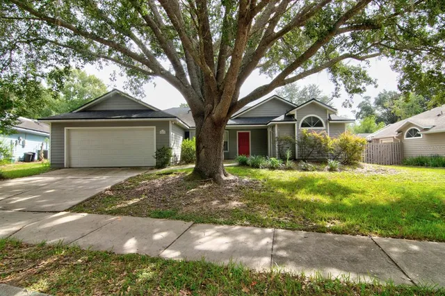 a front view of a house with a garden and trees