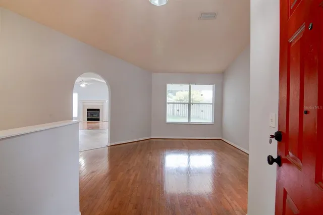 an empty room with wooden floor and windows