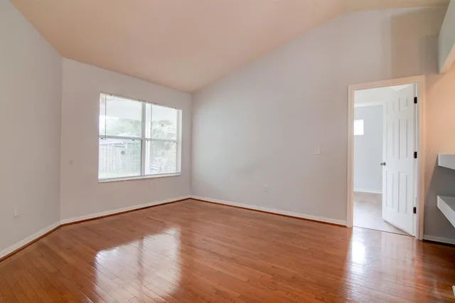 an empty room with wooden floor and windows