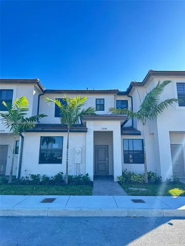 a front view of a house with garage and plants
