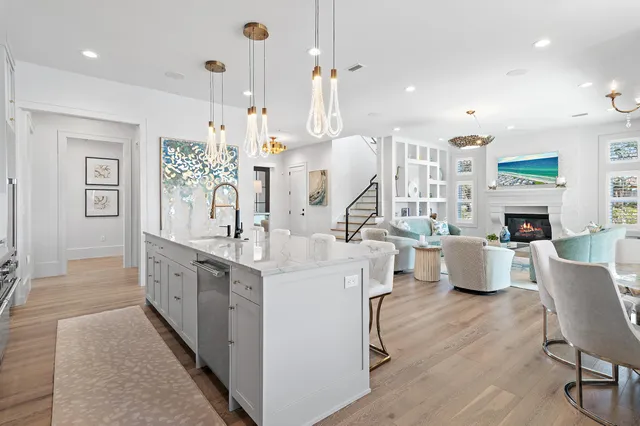 a large white kitchen with a large island oven a sink dishwasher a dining table and chairs with wooden floor