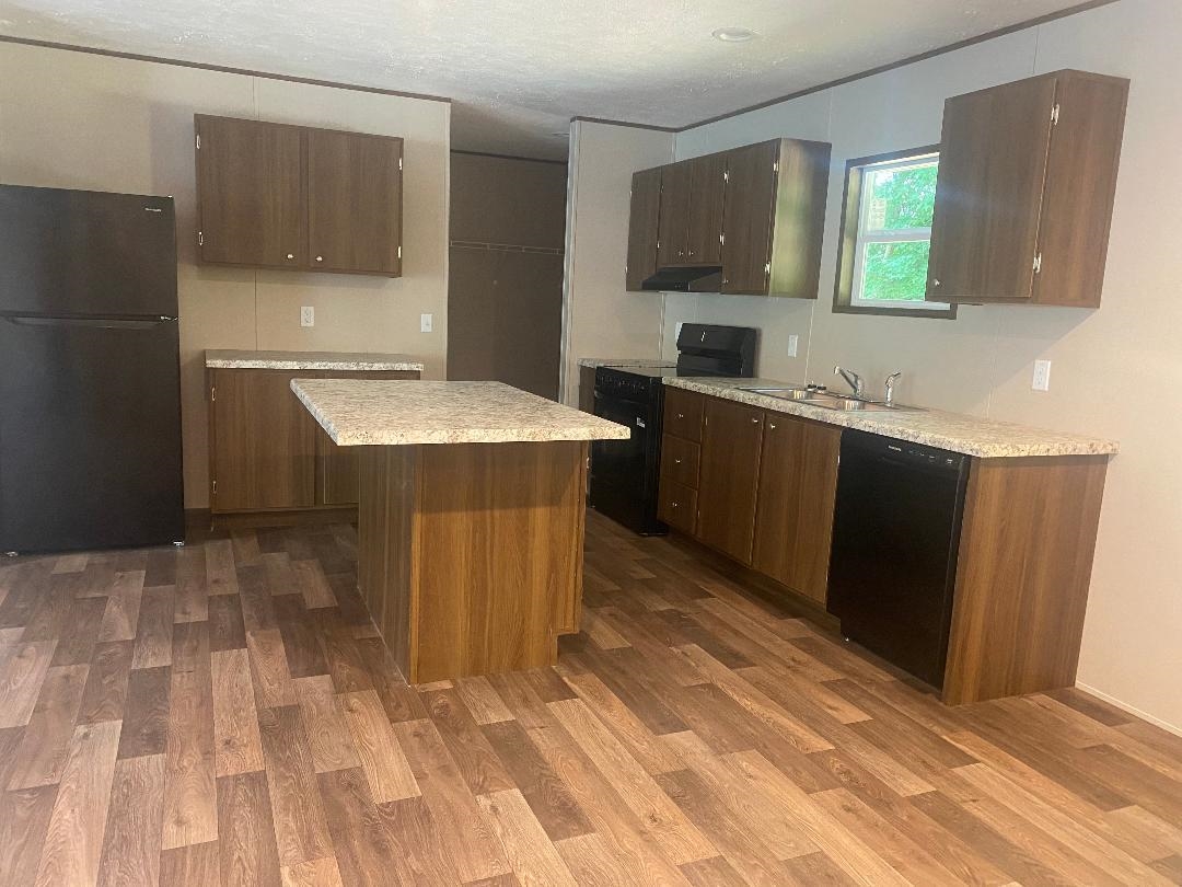 106 Simmons Road Munford, TN 38058 - Photo 4 of 30 Wood-finish flooring, central island with countertop, dark wood-finish cabinetry, black appliances, and a stainless steel sink