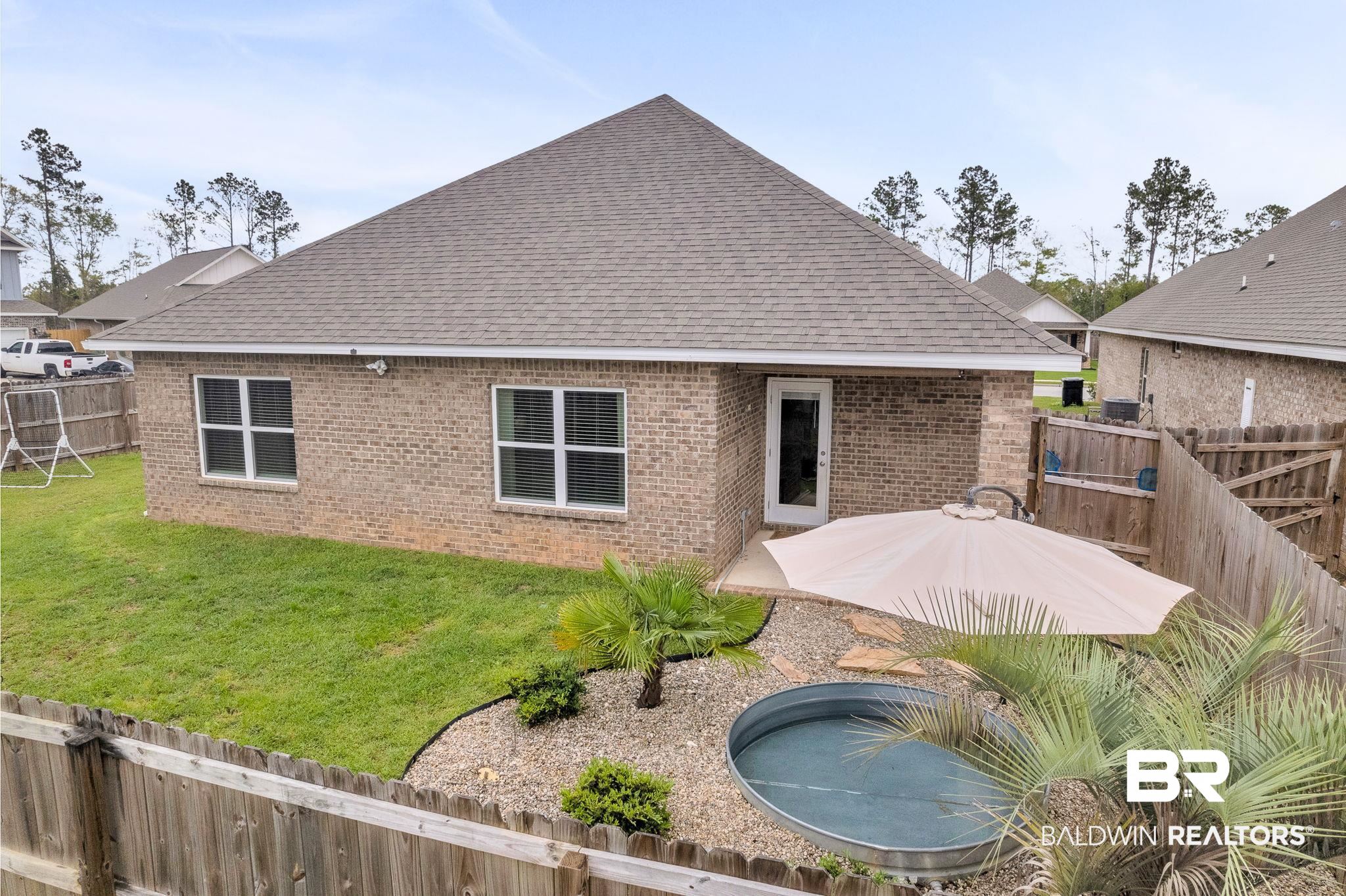 31650 Memphis Loop Daphne, AL 36527 - Photo 50 of 68 Rear view of house featuring a fenced backyard, roof with shingles, brick siding, and a patio area