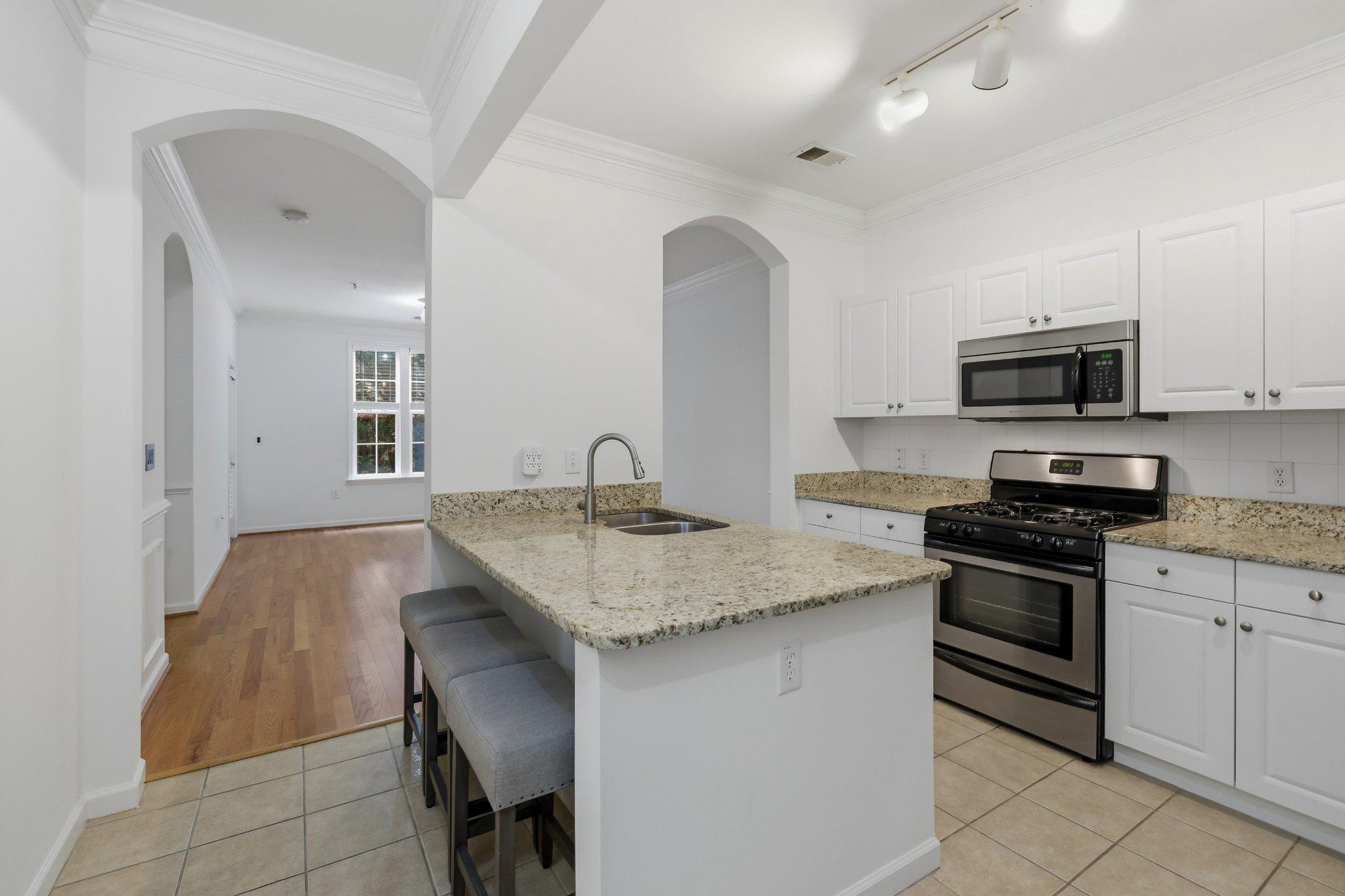 31 Booth Street, Unit B55 Gaithersburg, MD 20878 - Photo 4 of 30 a kitchen with stainless steel appliances granite countertop a stove top oven a sink a dining table and chairs