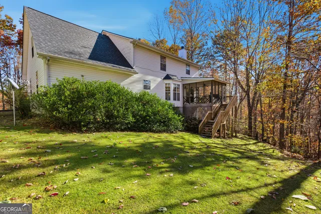 a view of swimming pool with lawn chairs and large trees