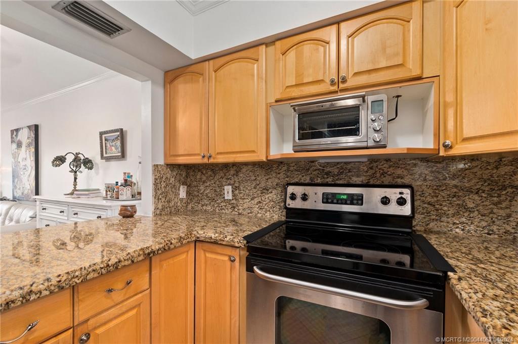 3135 Southeast Indian Street, Unit 5 Stuart, FL 34997 - Photo 11 of 41 a kitchen with granite countertop cabinets stove top oven and microwave