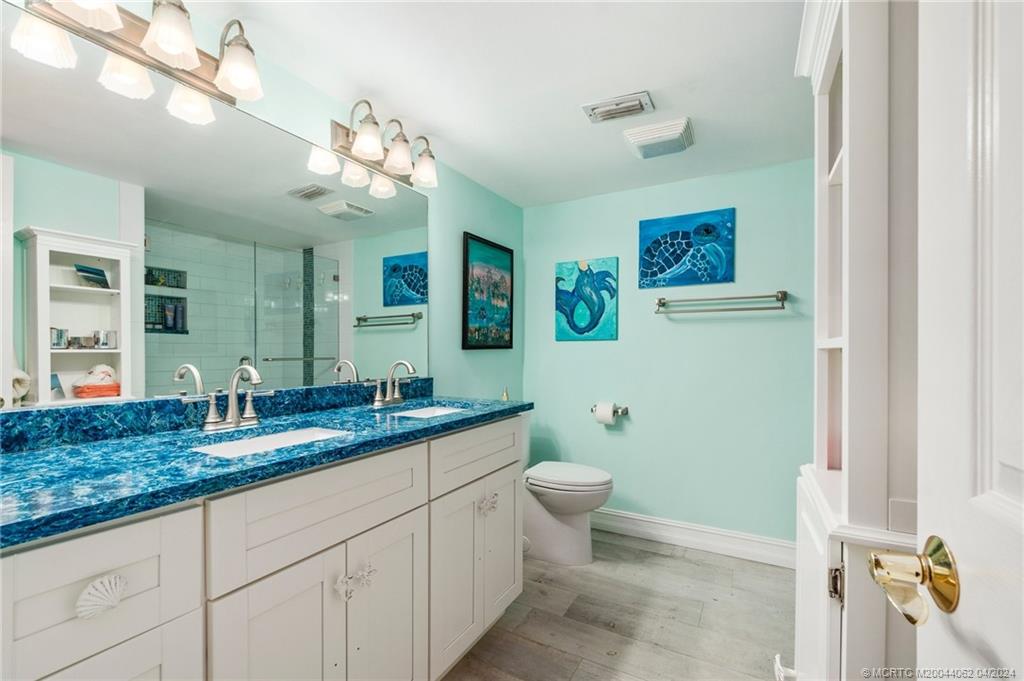3135 Southeast Indian Street, Unit 5 Stuart, FL 34997 - Photo 27 of 41 a bathroom with a granite countertop sink a toilet and a mirror