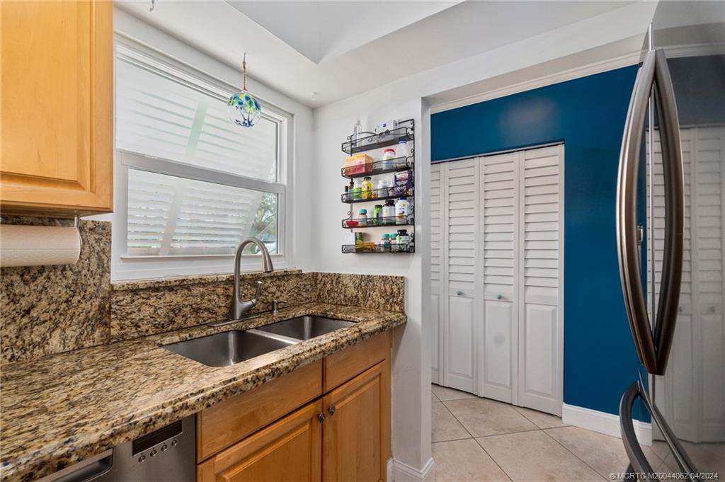 3135 Southeast Indian Street, Unit 5 Stuart, FL 34997 - Photo 8 of 41 a kitchen with granite countertop a sink and a refrigerator