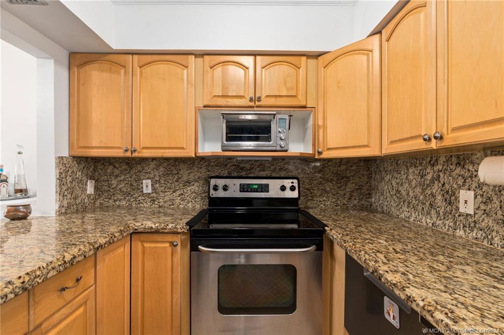 3135 Southeast Indian Street, Unit 5 Stuart, FL 34997 - Photo 10 of 41 a kitchen with granite countertop a stove top oven microwave and cabinets