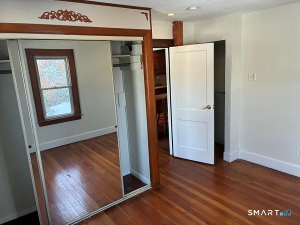 an empty room with wooden floor and a large window