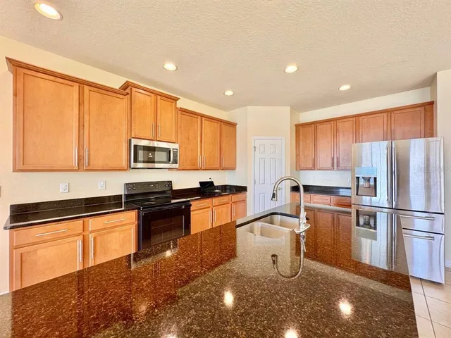 a kitchen with stainless steel appliances granite countertop a sink stove and refrigerator