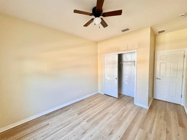 a view of a room with wooden floor and a ceiling fan