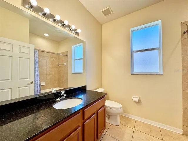 a bathroom with a granite countertop sink a toilet and a mirror