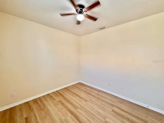 an empty room with a window and a ceiling fan