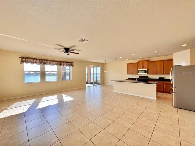 a large kitchen with stainless steel appliances kitchen island granite countertop a refrigerator and a stove top oven