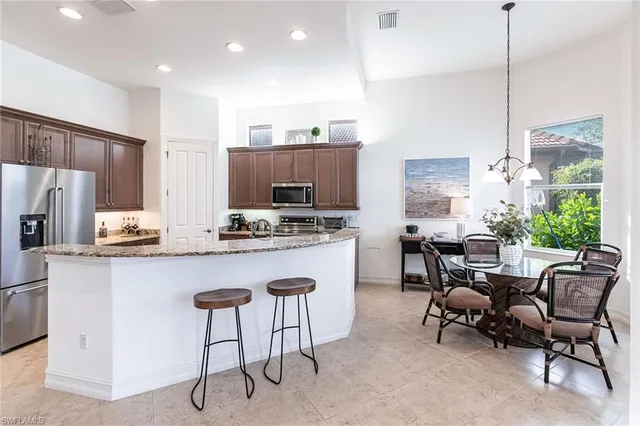 a kitchen with kitchen island granite countertop a table chairs stove a sink and a view of living room