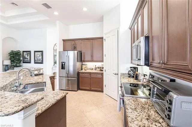a kitchen with stainless steel appliances kitchen island granite countertop a sink stove and refrigerator