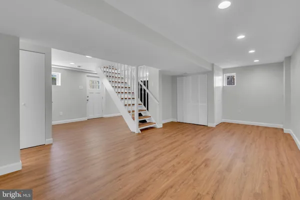 a view of an empty room with wooden floor and stairs