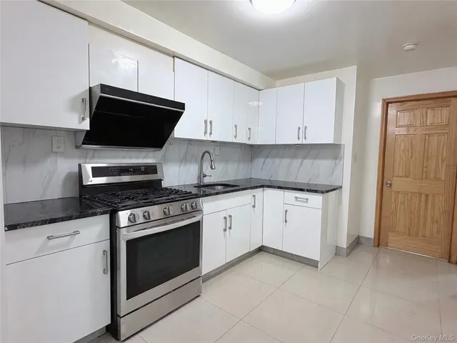 a kitchen with granite countertop white cabinets and stainless steel appliances