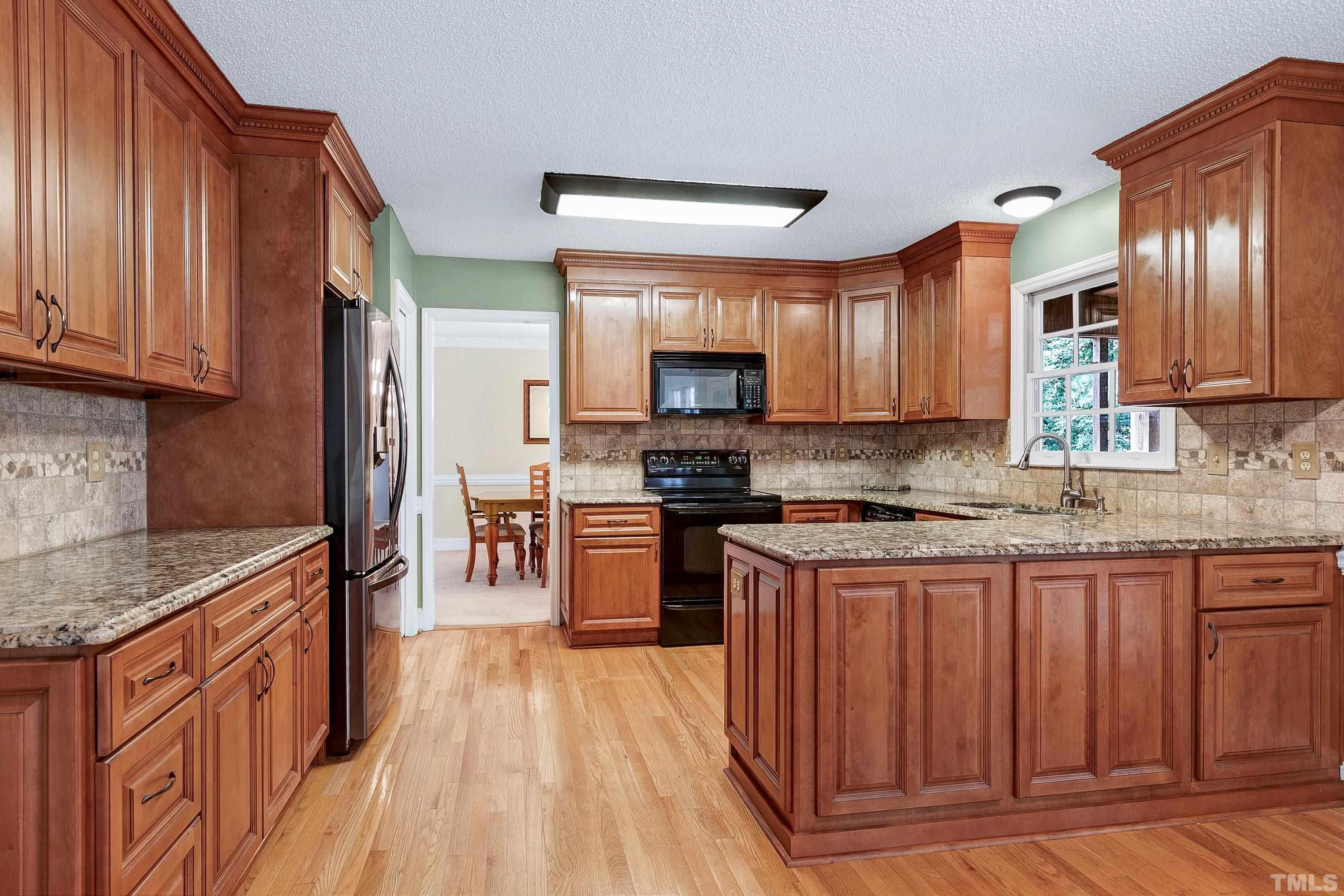 117 Trailing Oak Cary, NC 27513 - Photo 8 of 32 a kitchen with granite countertop wooden floors wooden cabinets a sink and appliances