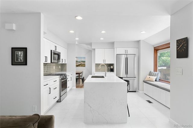 a large white kitchen with stainless steel appliances lots of white cabinets