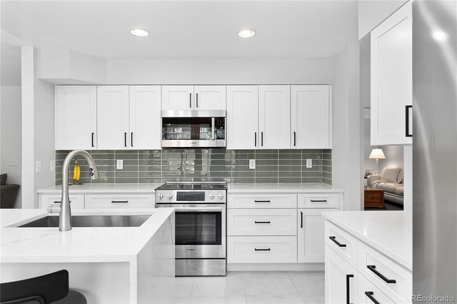 a kitchen with white cabinets stainless steel appliances and sink