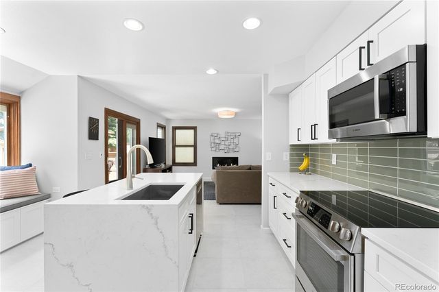 a kitchen with stainless steel appliances kitchen island granite countertop a sink and stove top oven with wooden floor