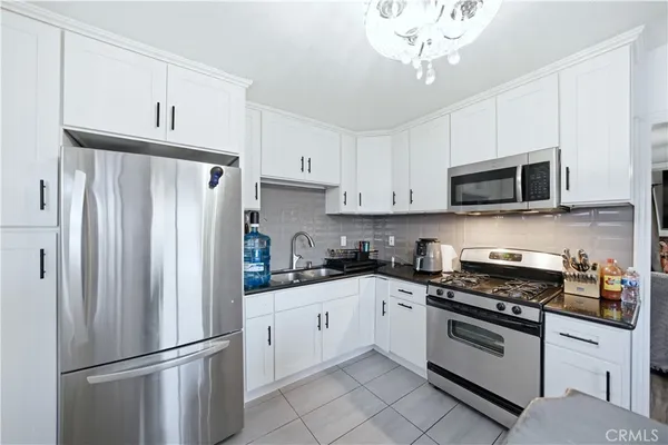 a kitchen with stainless steel appliances a refrigerator stove and white cabinets