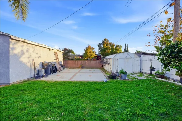 a backyard of a house with table and chairs plants and large tree