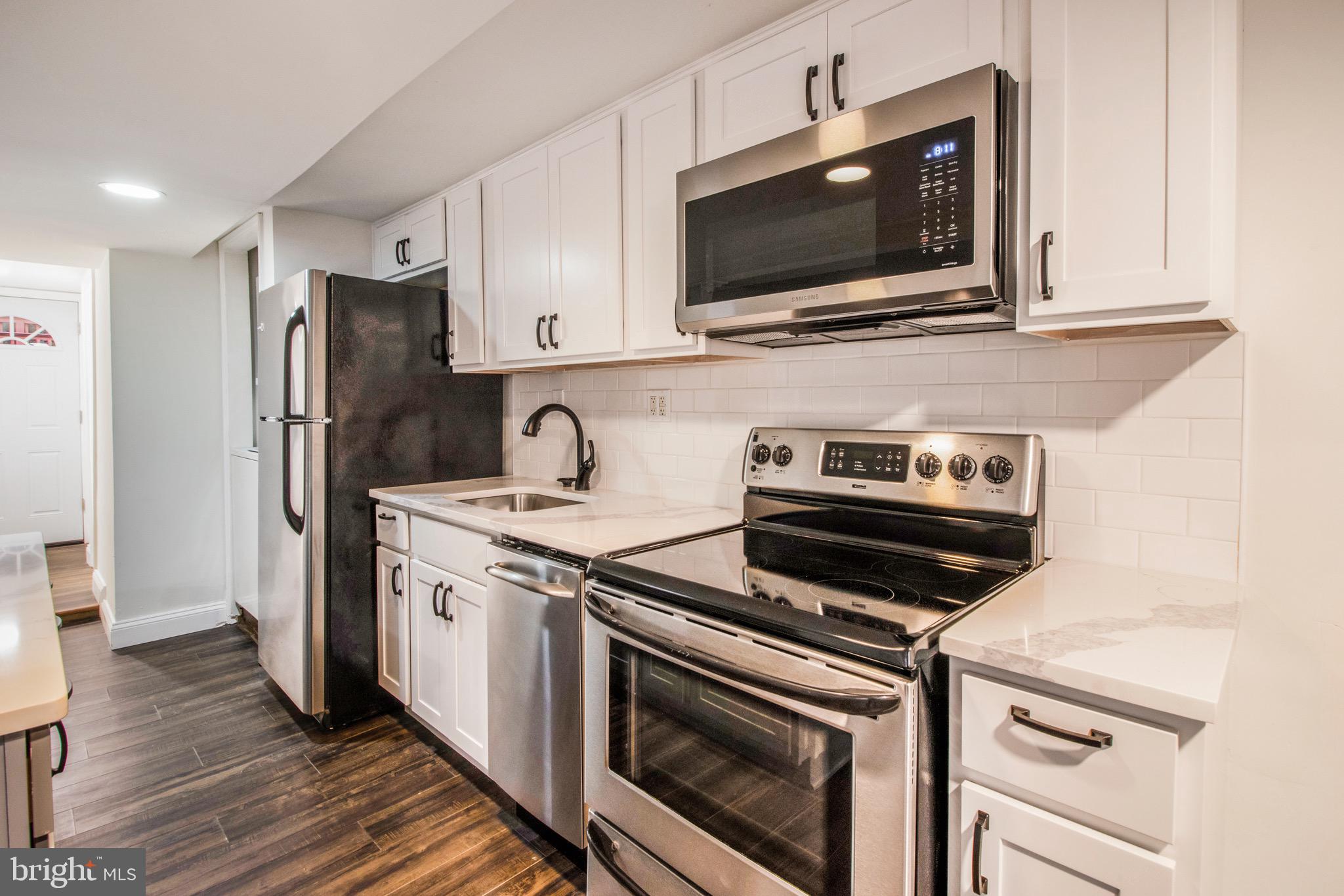 104 15th Street Southeast, Unit B Washington, DC 20003 - Photo 5 of 18 a kitchen with stainless steel appliances a stove a microwave and cabinets