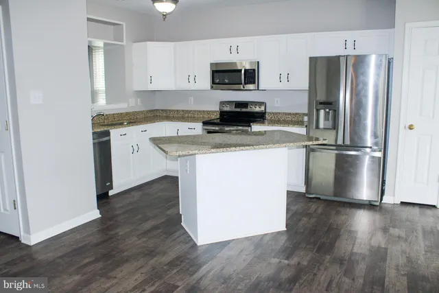 a kitchen with stainless steel appliances granite countertop a refrigerator stove a sink and a microwave