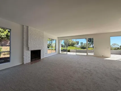 a view of an empty room with wooden floor and a fireplace