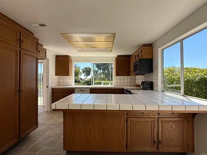 a kitchen with stainless steel appliances kitchen island granite countertop a refrigerator a stove and a wooden cabinets