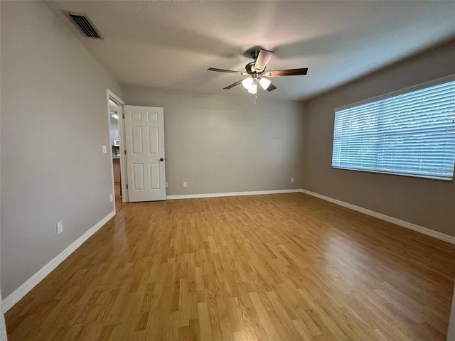 a view of empty room with wooden floor and fan