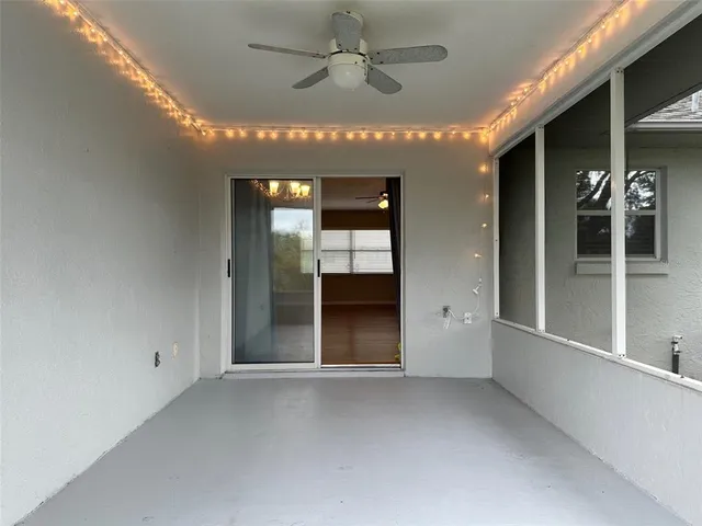 an empty room with chandelier fan and windows