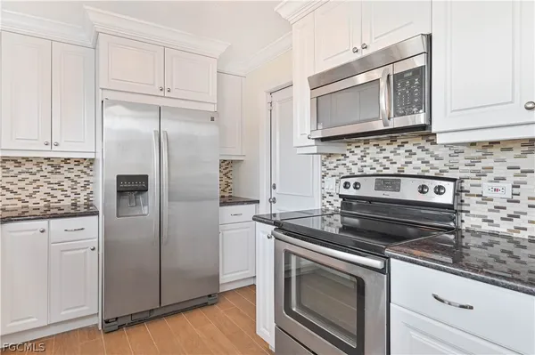 a kitchen with granite countertop cabinets stainless steel appliances and wooden floor