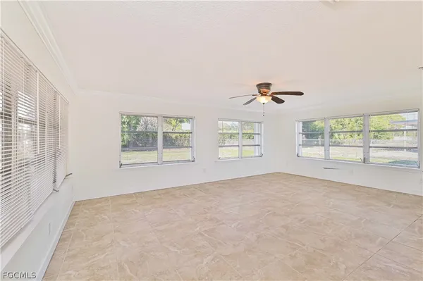 an empty room with windows and ceiling fan