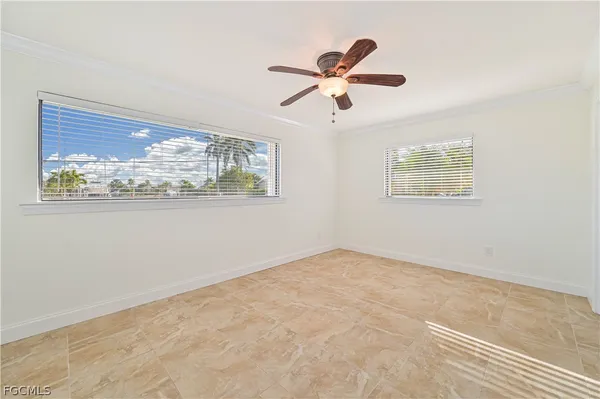 an empty room with wooden floor fan and windows