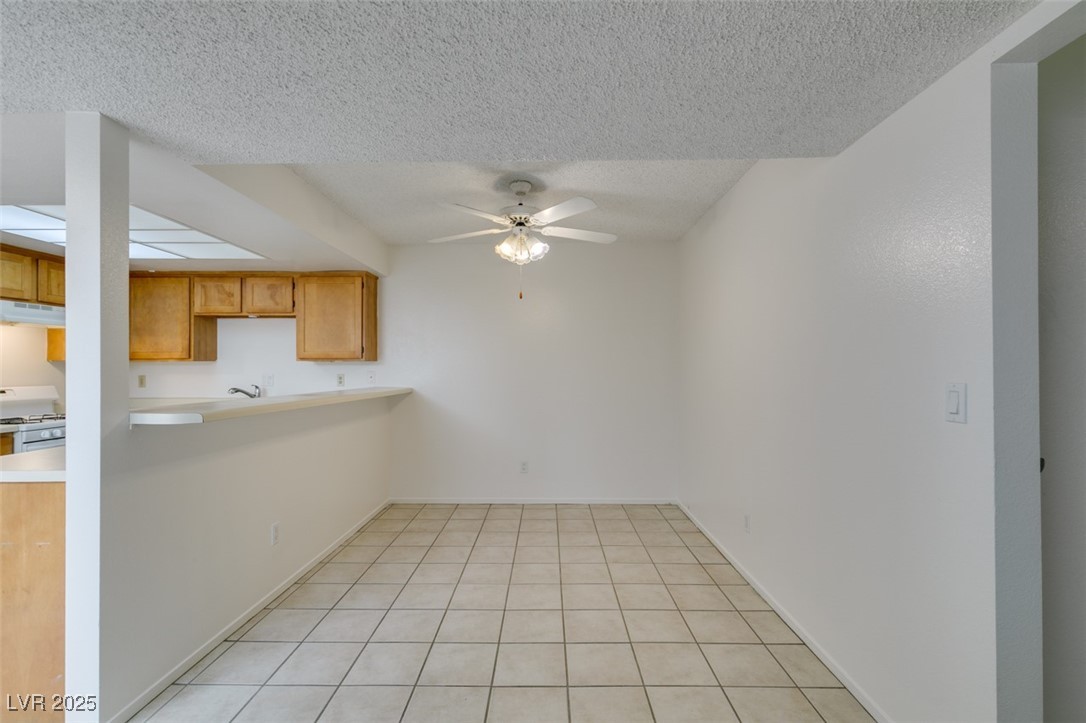 2681 Ruthe Duarte Avenue Las Vegas, NV 89121 - Photo 15 of 43 Kitchen with white gas stove, under cabinet range hood, a textured ceiling, and ceiling fan