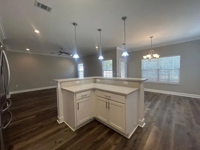 a open kitchen with kitchen island white cabinets and wooden floor