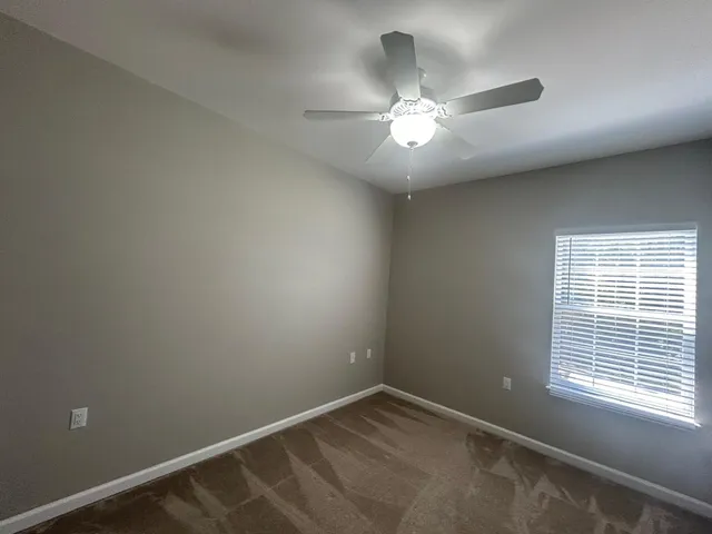 an empty room with a window and a fan