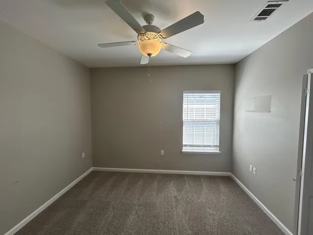 an empty room with a window and a fan